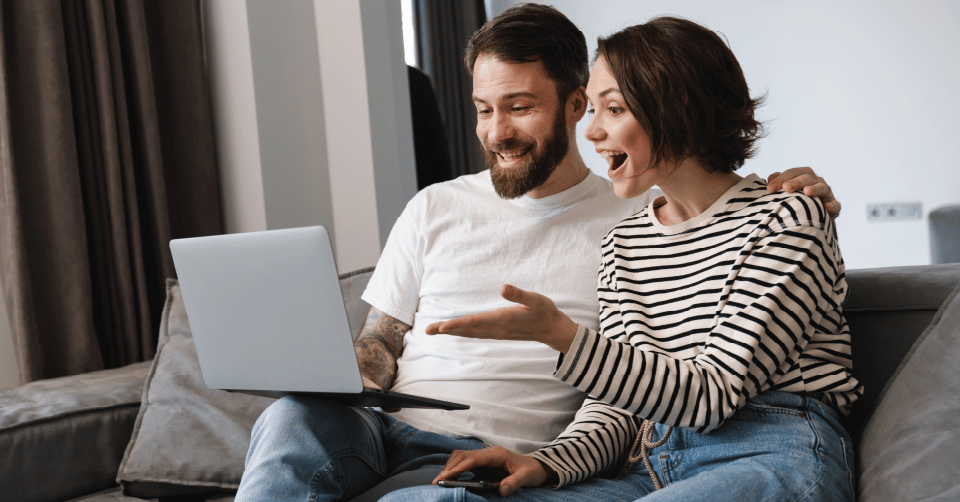 young couple happily views media on their laptop